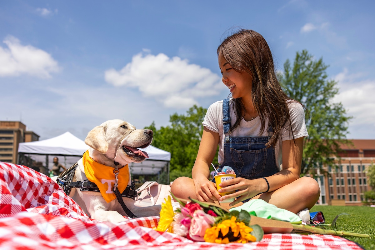 A training service dog and student relax during Garden Party