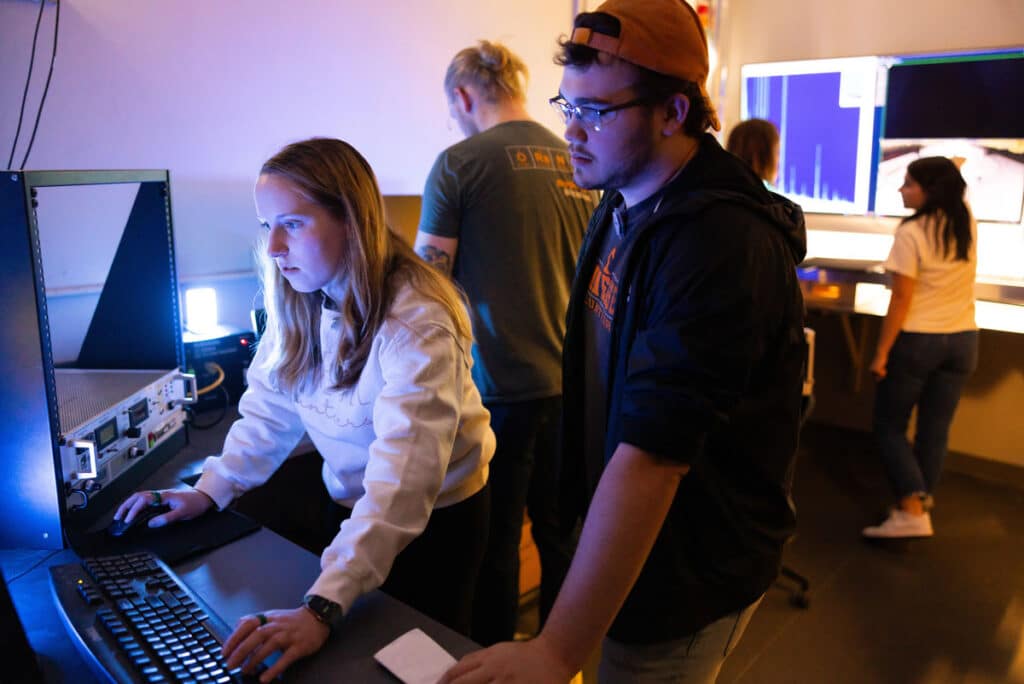 Graduate and undergraduate students working in the control room during an experiment with the fast neutron source