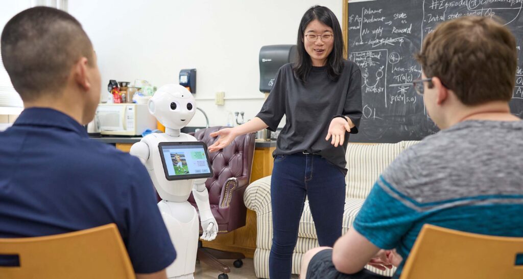 Graduate students works with robot in robotic assistance lab.