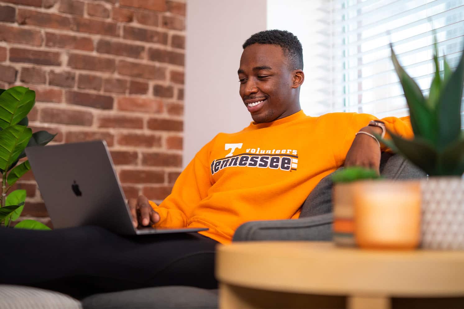 Student sits with laptop inside apartment