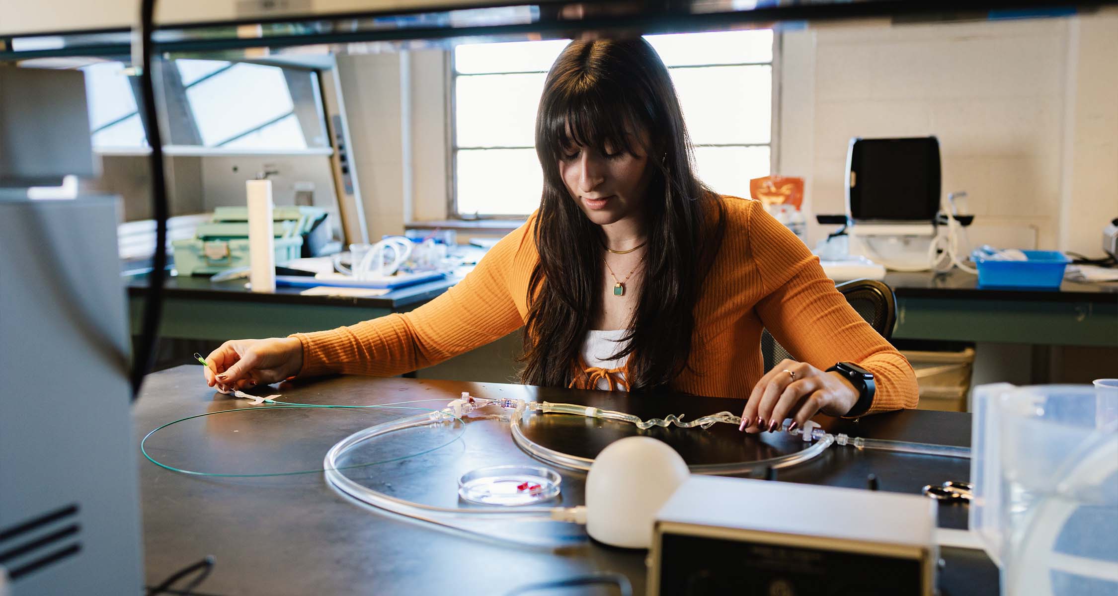 Student works with fluid dynamics testing equipment in biomedical engineering lab.