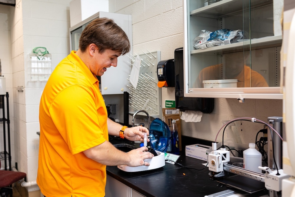 David working on a machine in a lab