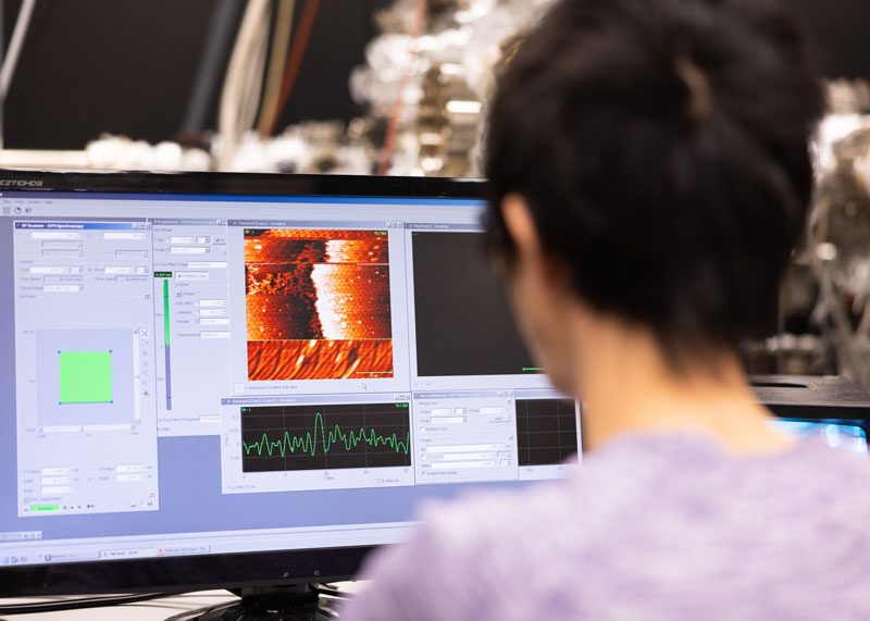 A graduate student works on a computer in the Molecular Beam Epitaxy Core Facility for a research photo