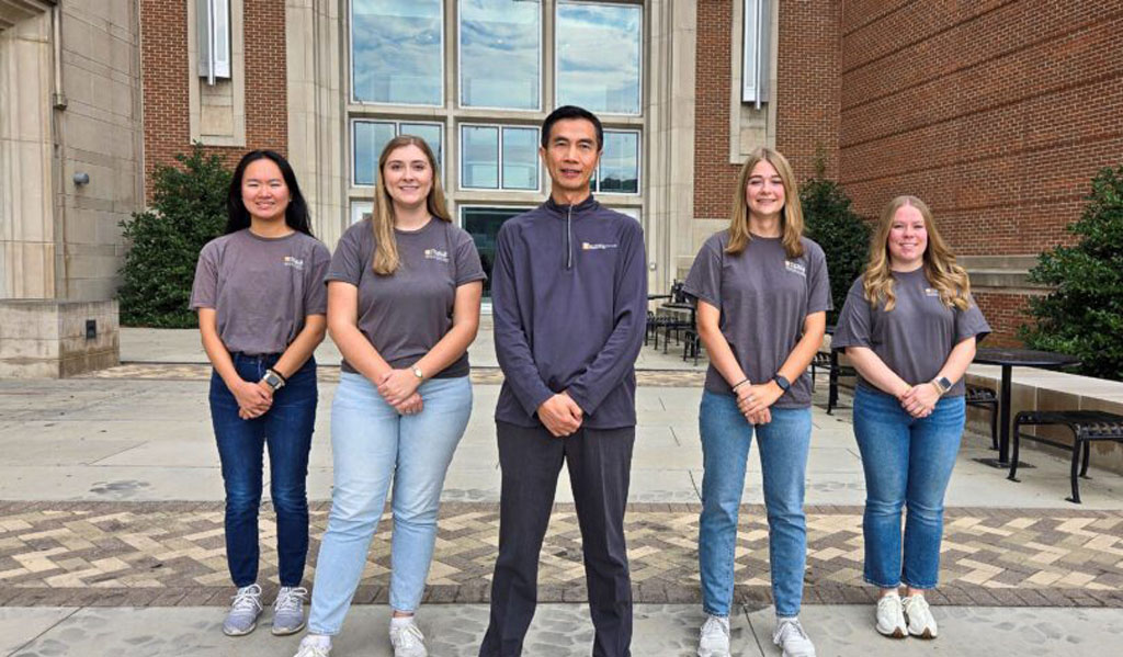 Alpha Pi Mu officers stand on the Tickle Engineering Building bridge. 