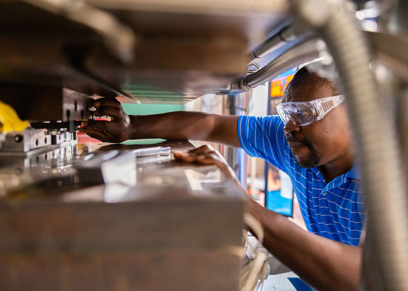 Romeo Sephyrin Fono-Tamo works with a Wabash, a 150-ton capacity large press, that makes panels from sheet molding compound in the Fibers and Composites Manufacturing Facility (FCMF) lab