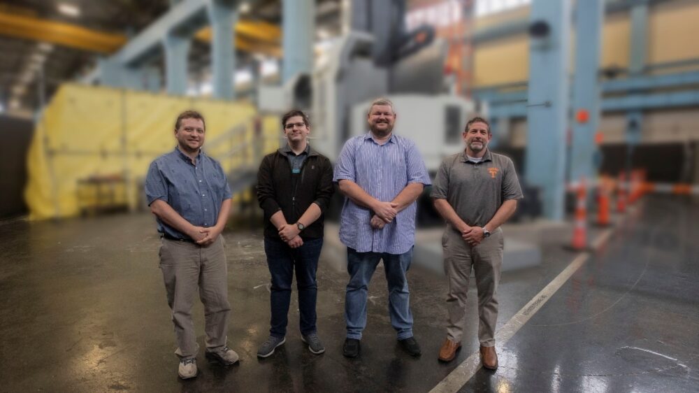 The Tooling Project Team pictured standing in front of a machine on the shop floor