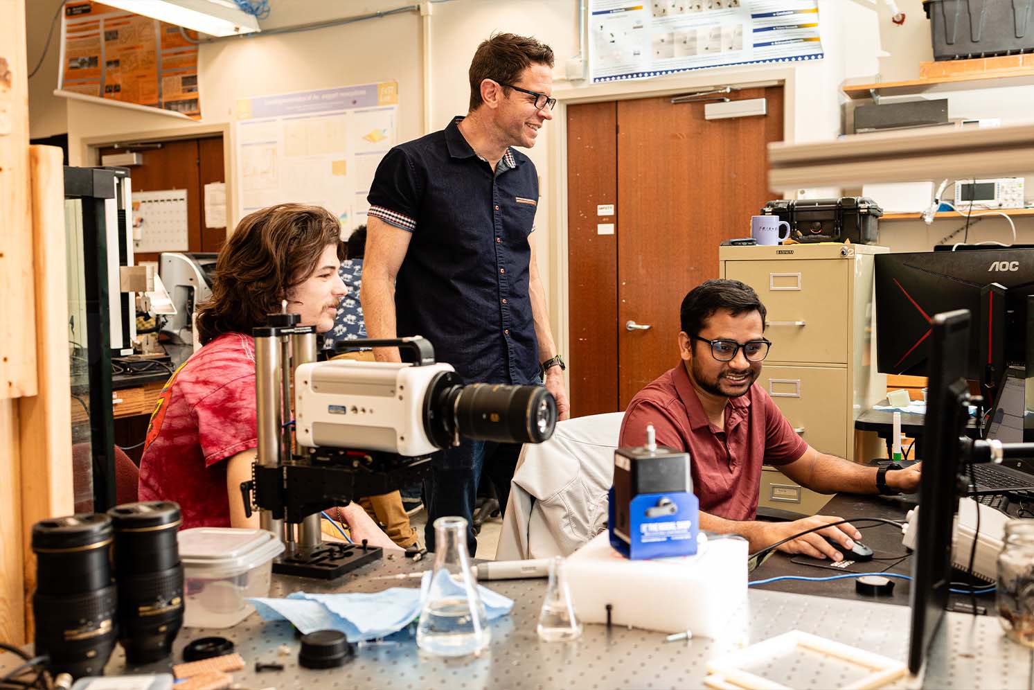 Andrew Dickerson works with two students in his lab