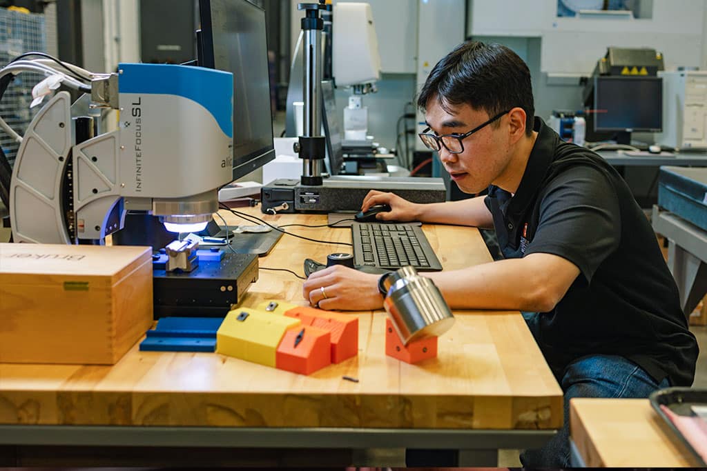 Graduate student test composites material under microscrope at TN-MADE.