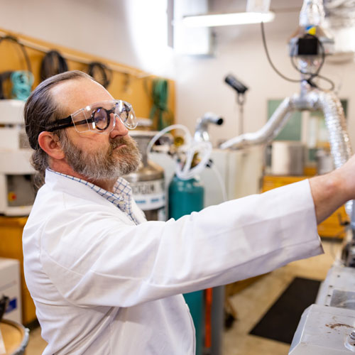 David Harper, a Joint UTK Associate Professor with Materials Science and Engineering, adjust the settings on an extruder machine inside a Center for Renewable Carbon (CRC) lab