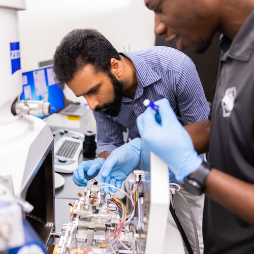 Stephen Puplampu and Vivek Chawla work with a nano scale mechanical testing system integrated in a Scanning Electron Microscope inside an IAMM lab