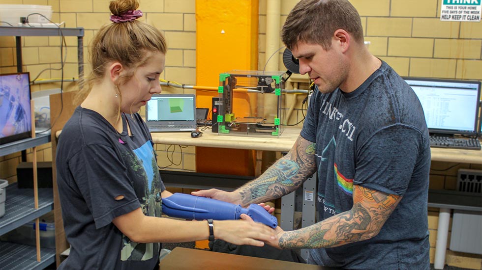 Alex Weber works with Riley Toll on 3D Printed Arm
