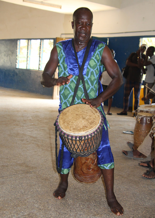 Man plays a drum he is wearing.
