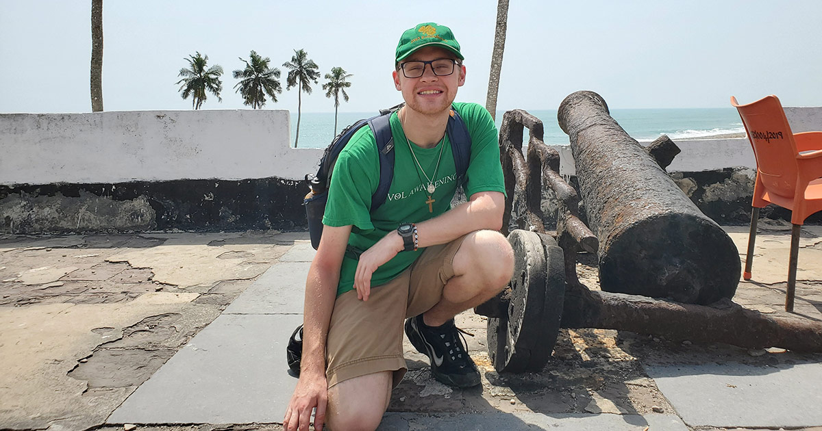 Christopher Cannon poses beside a cannon.