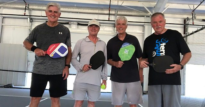 Lee Martin and three other men hold pickleball paddles.