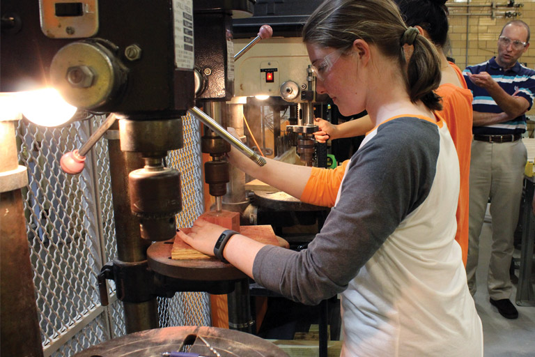 Female student using woodworking equipment
