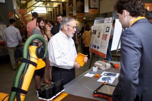 Professor Bill Hamel learns about the design these students developed for a robotic device that will clean automotive dashboard glass.