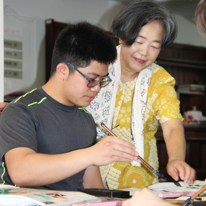 Matthew learns Japanese calligraphy with the help of a teacher.