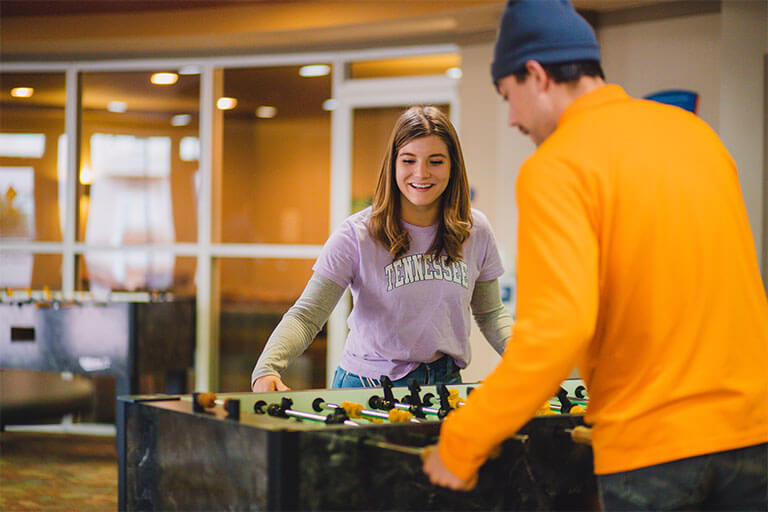 Two students play table soccer in campus housing