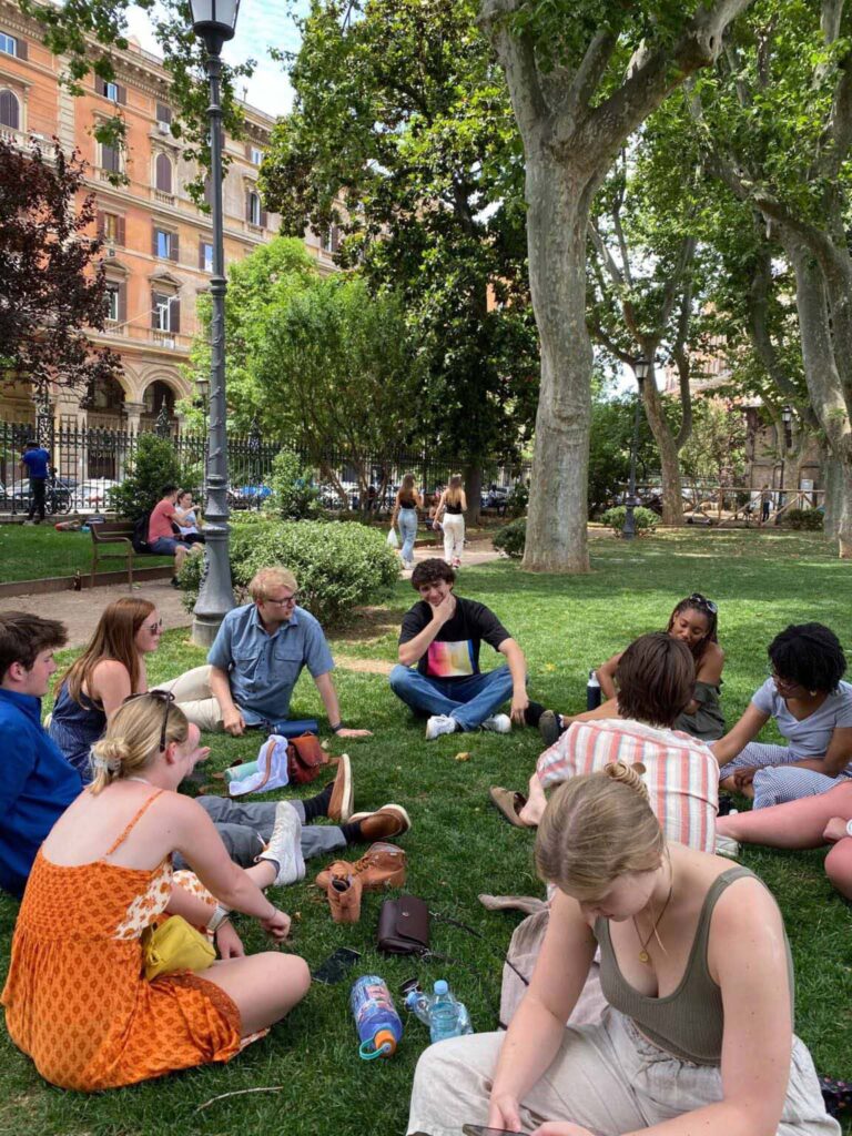 Students and professor studying on lawn in Italy