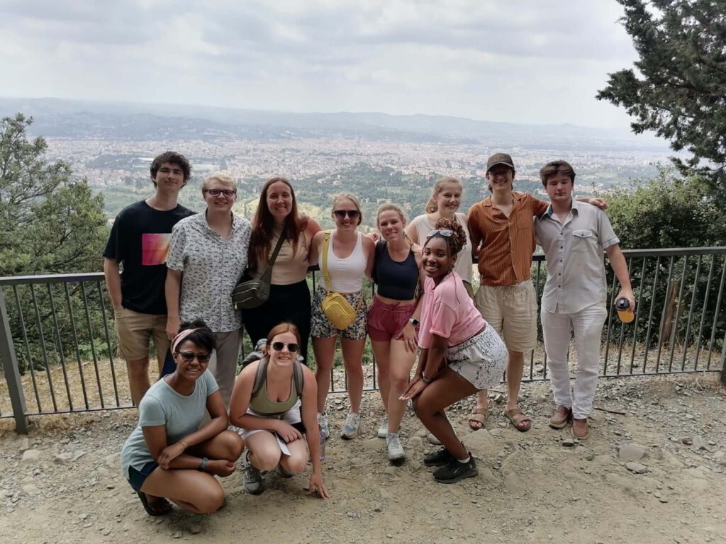 Annabeth and a group of students posing for photo in front of Italian landscape