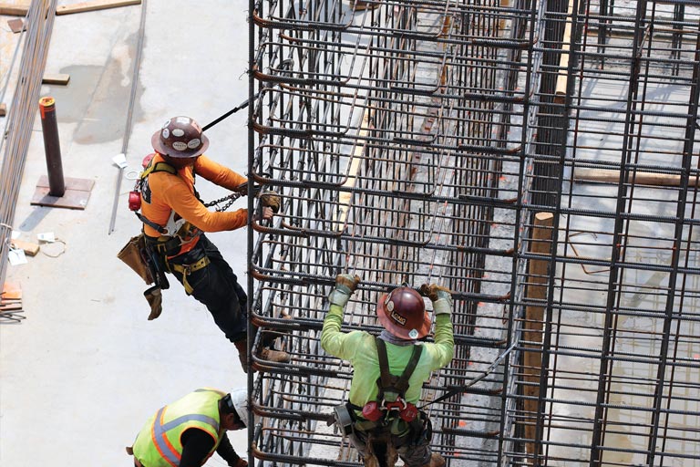Workers prepare the complex lattice of rebar to hold the new building’s substantial concrete foundation.