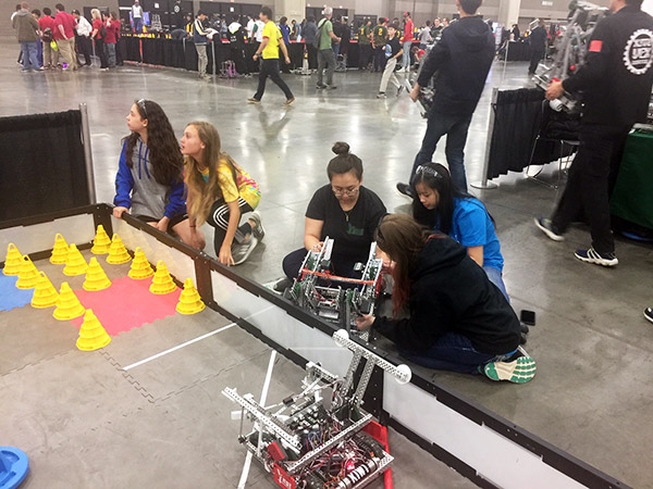 Team YNOT member, Clare Remy (middle), assists a middle school team from South Carolina with modifications at the 2018 Vex Robotics world championship.