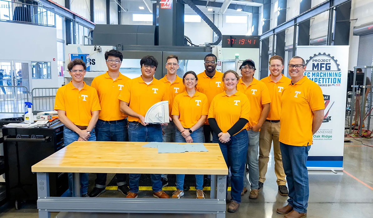 UT machining students in matching orange team polo shirts pose with their winning quadrant of the S.E.C. logo.