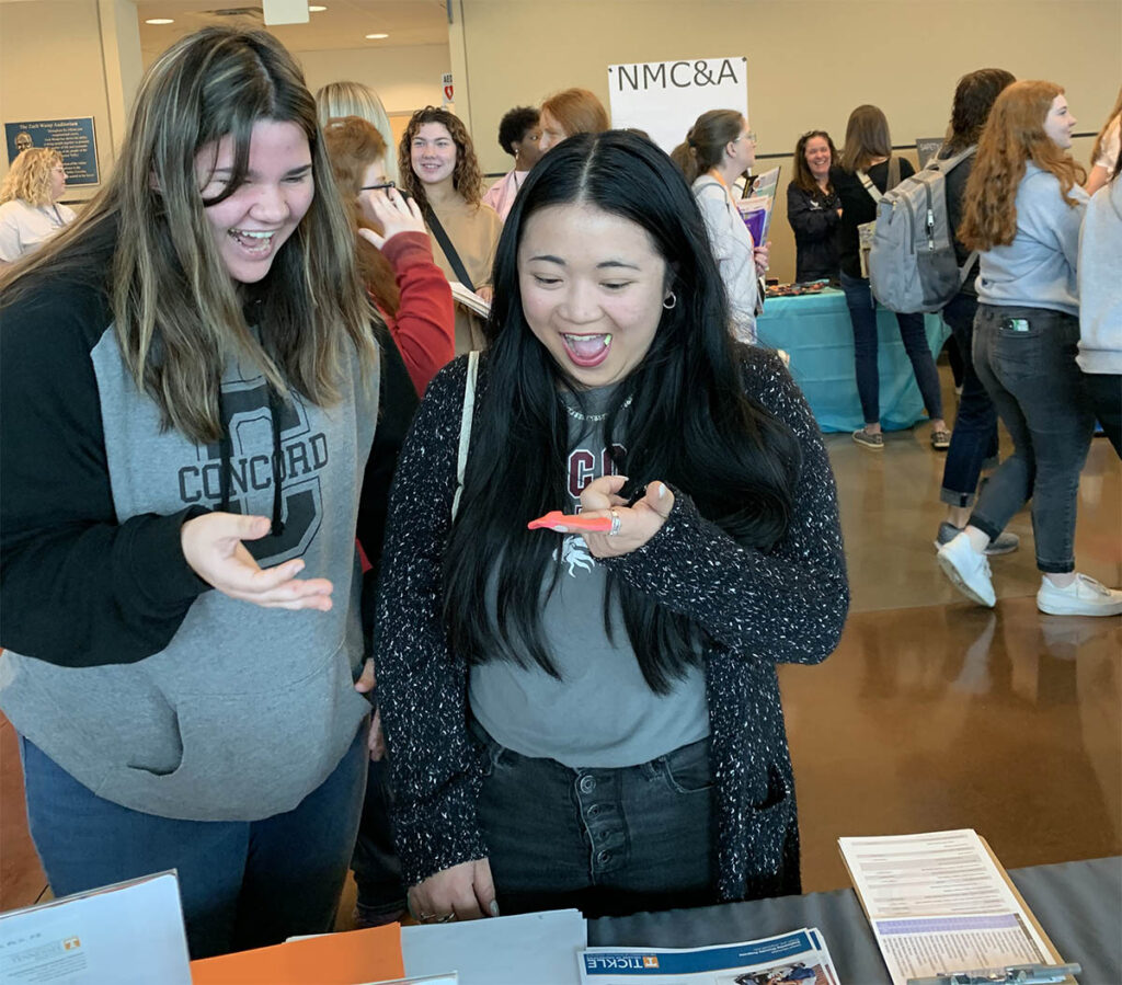 Women engineering students test swag items at the registration table
