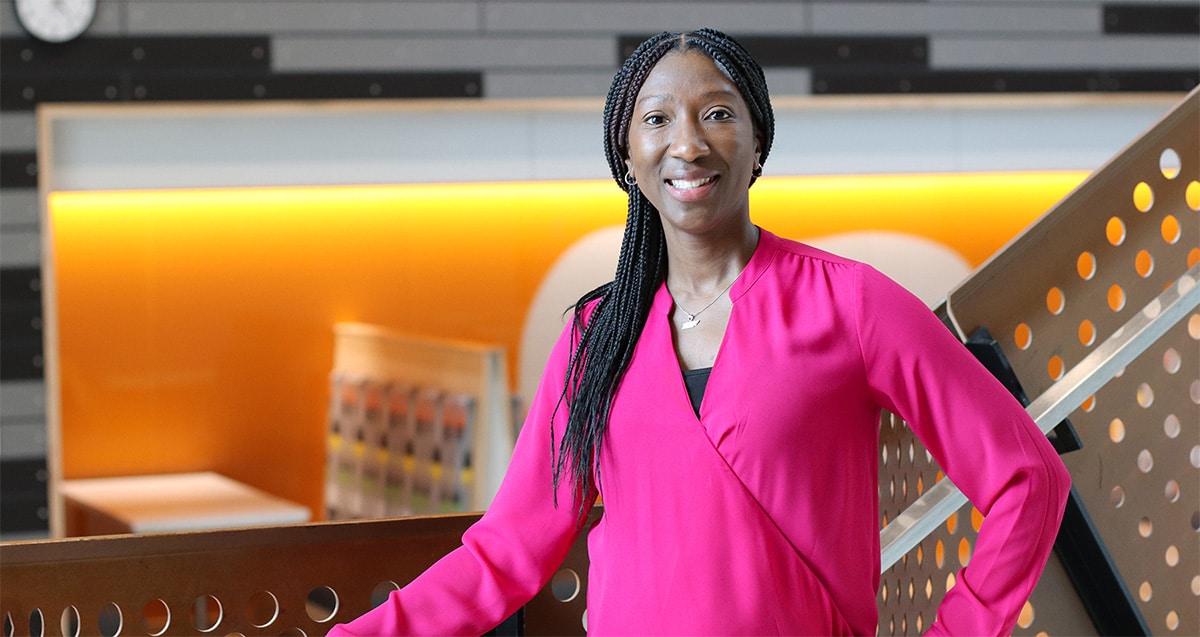 Jalonda Thompson smiling, dressed in a long-sleeve pink shirt, standing in the 5th floor of Zeanah Engineering Complex.