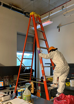 EMB researcher climbs down a ladder while conducting research related to COVID-19