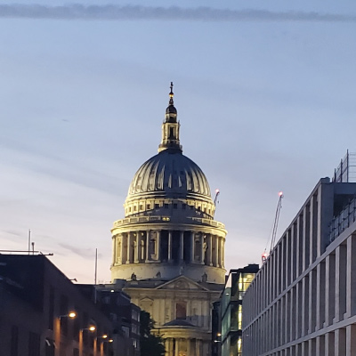 St. Pauls Cathedral in London, England illuminated by a setting sun against a dusk evening sky.
