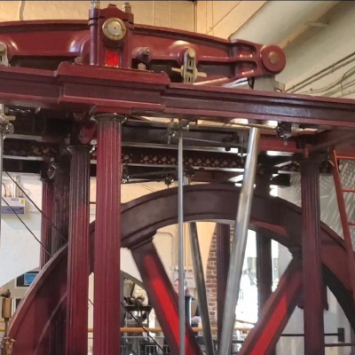 A maroon colored steam engine located inside of the London Museum of Water and Steam.