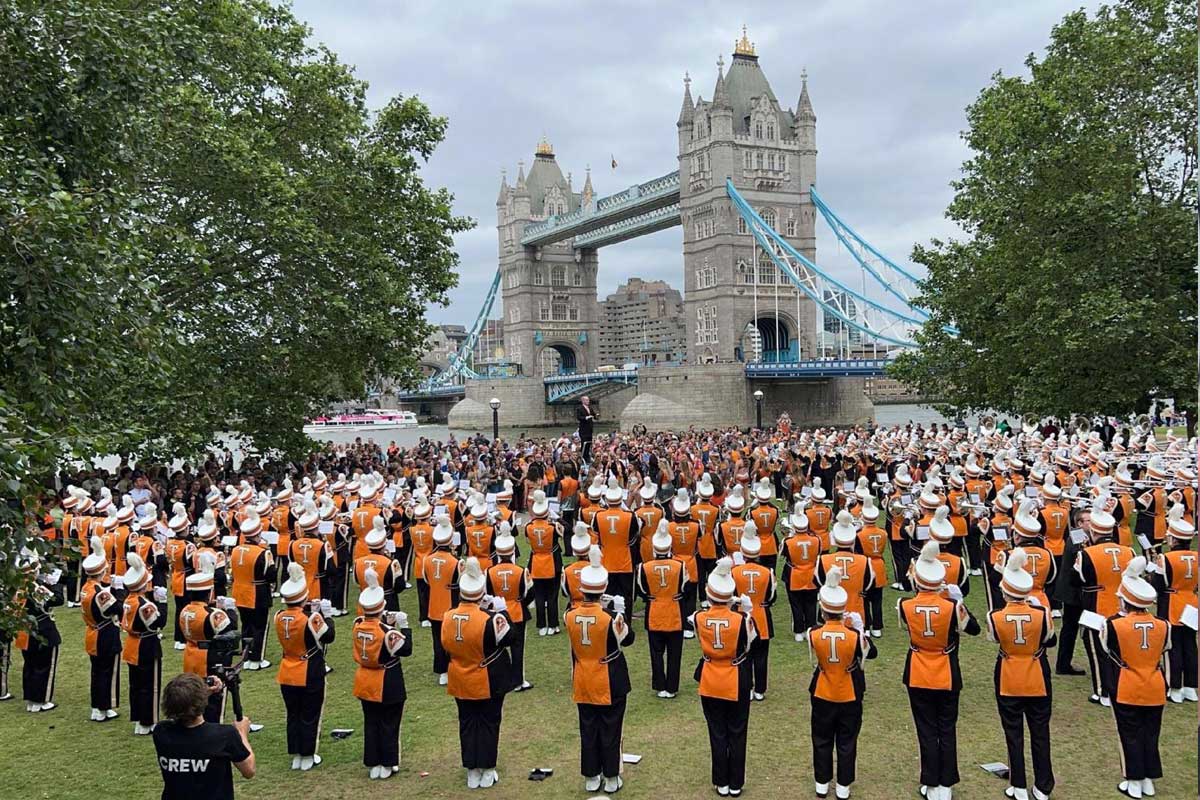 The University of Tennessee Knoxville's "Pride of the Southlands" Band performs in London, England. The band is dressed in orange tops and black pants.