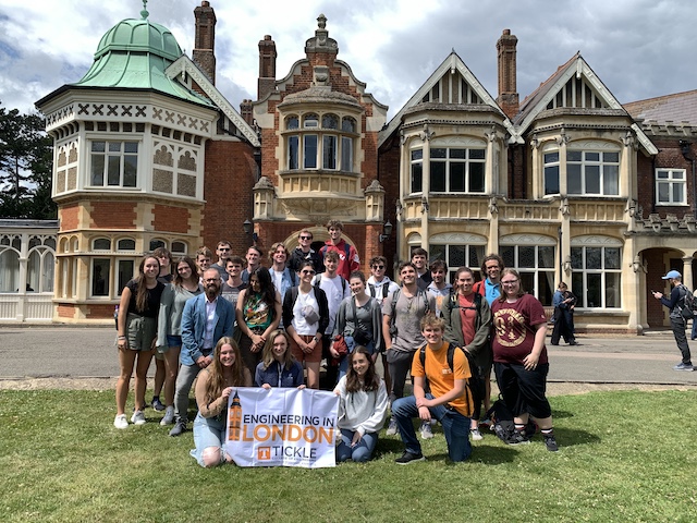 Colby Hale and the Engineering in London study abroad group stand together for a group photo in Bletchley Park while holding an Engineering in London banner.