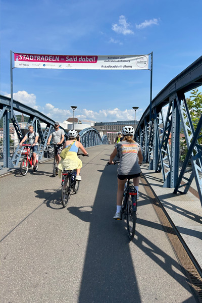 Two groups of bicyclists passing one another as they traverse a pedestrian bridge in Germany.