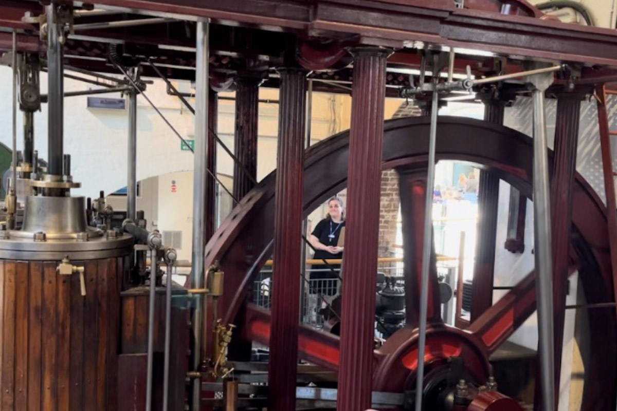 A maroon colored steam engine located inside of the London Museum of Water and Steam.