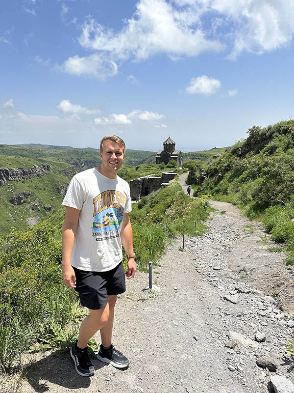 Parker Bowling, wearing a Tennessee t-shirt and black shorts, stands on a gravel path during his study abroad trip.