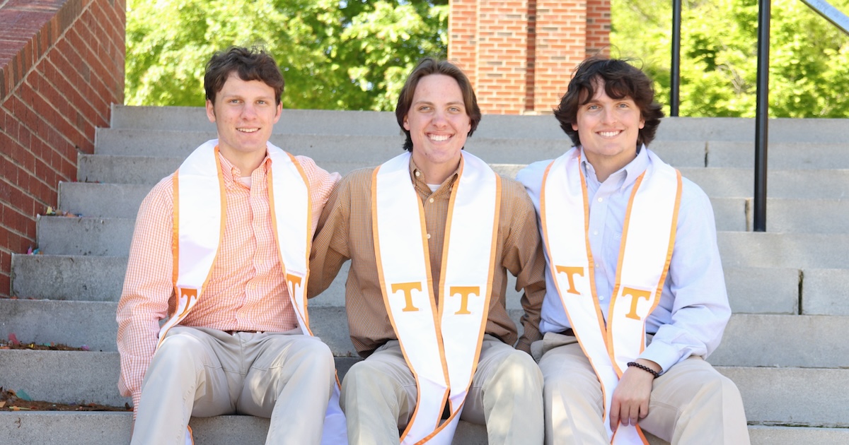 Walker, Jackson, and Grey Reeves sitting on outdoor steps wearing their graduation sashes