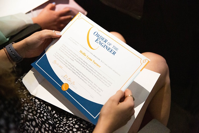 Student inspects their certificate during the ceremony, 