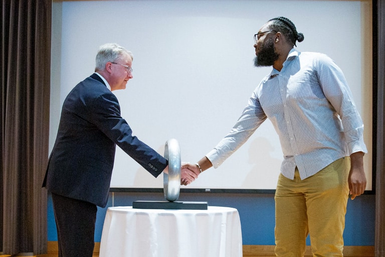 Graduate shakes CEE Department Head Chis Cox's hand through the ring. 