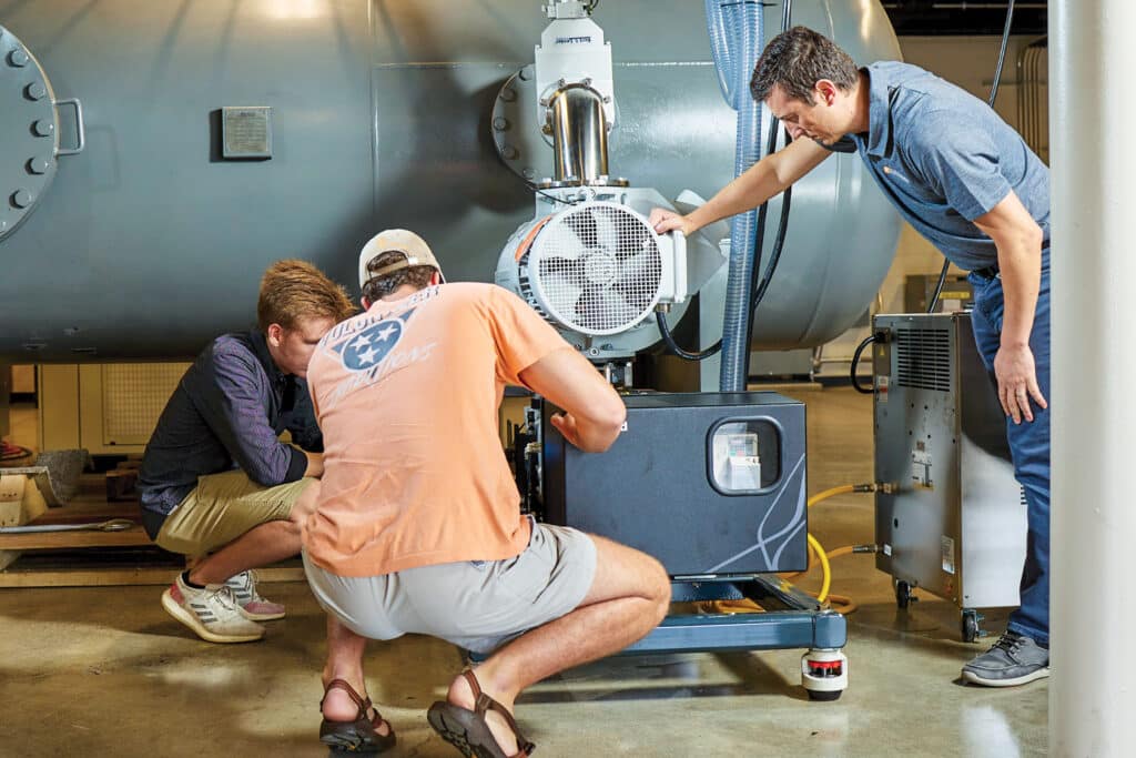 Two students work with Damiano Baccarrella on the Arcjet Wind Tunnel