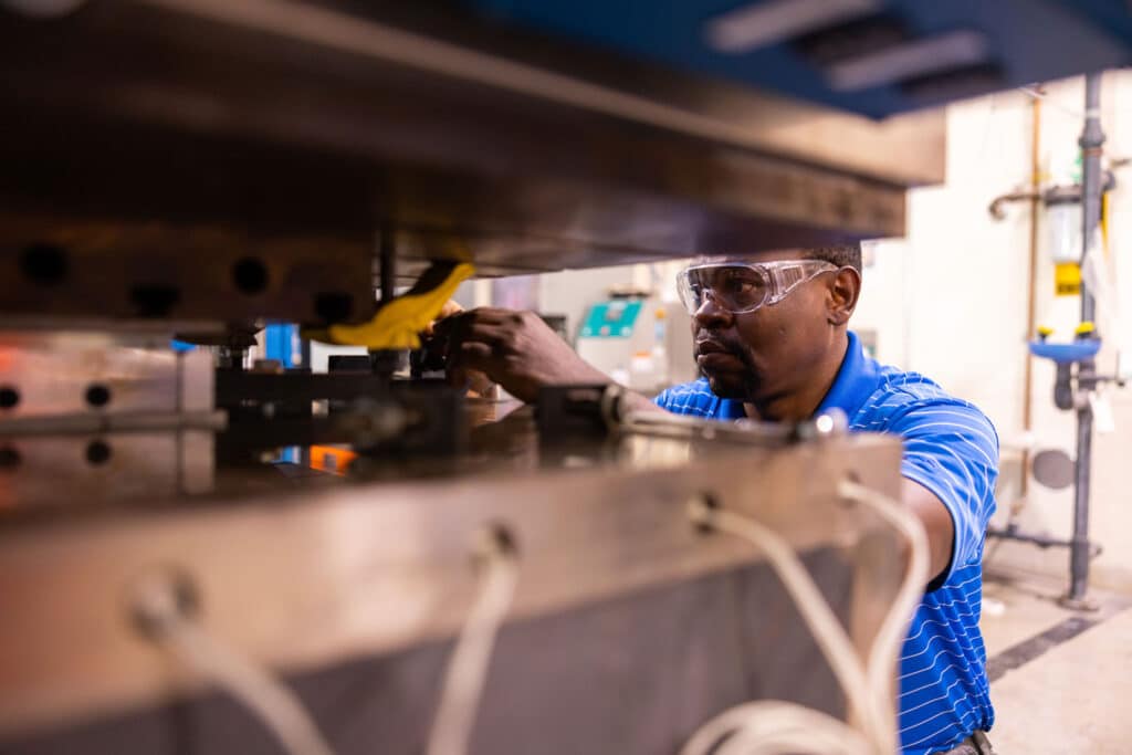 Romeo Sephyrin Fono Tamo works with a Wabash, a 150-ton capacity large press, that makes panels from sheet molding compound in the Fibers and Composites Manufacturing Facility (FCMF) lab