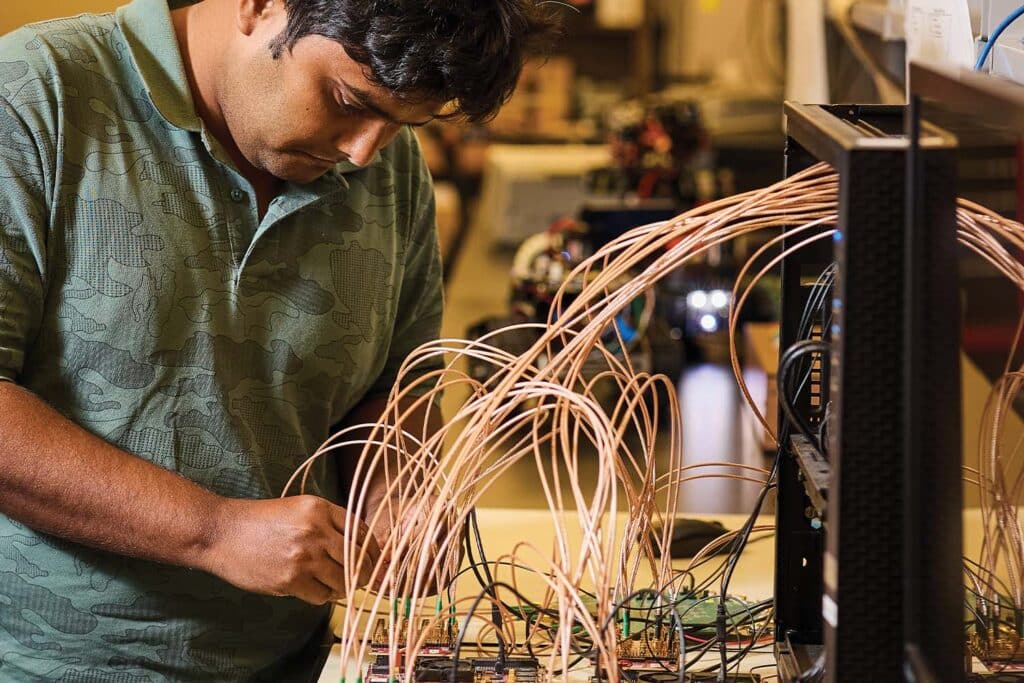Student works with circuit board inside Min Kao Engineering Building lab.