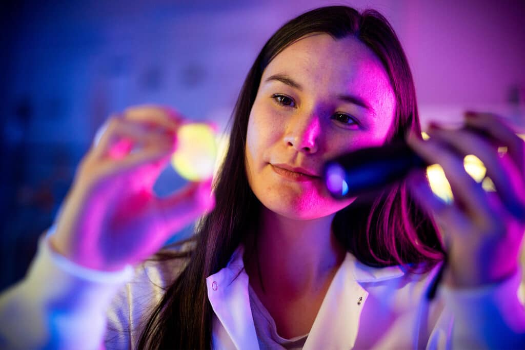 A student uses a black light to examine materials that absorb energetic radiation inside the Scintillation Materials Research Center.