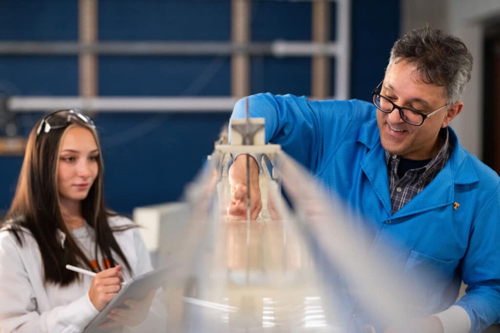 Research Associate and Technical Manager Adrian Gonzales walks graduate student Savannah Jobkar through a test using a flume in the Water Resources/Hydraulics Lab