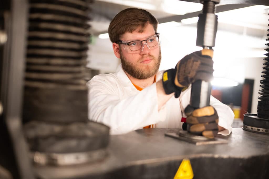 Graduate student Paxton Lifsey conducts a tensile test of a steel bolt using an Instron Universal Testing Machine in a lab in the John D. Tickle Engineering Building.