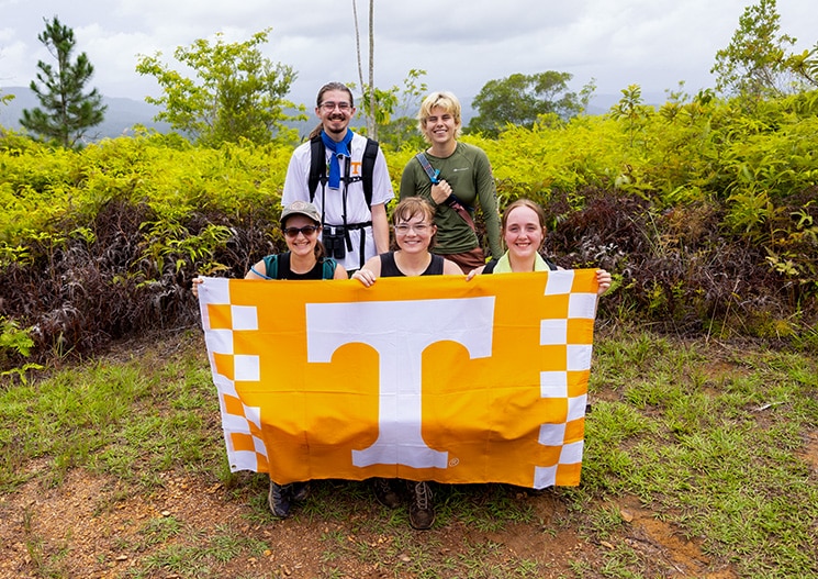 Students from the University of Tennessee display a flag from a hike during a study abroad trip. 