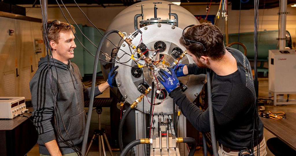 Two students work on the arcjet wind tunnel.