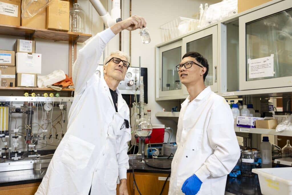 Frank Loeffler and Guang He looking at something in a tube