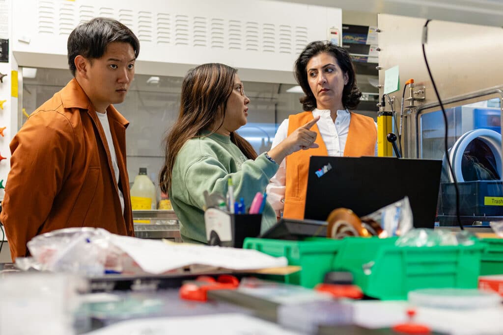 Mahshid Ahmadi works with two UT grad students with automated spin bot in a materials synthesis lab. 